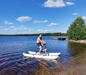 Mies pyöräilee vesipyörällä aurinkoisella järvellä