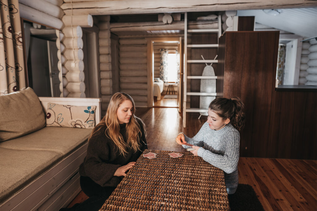 two young women playing cards in cabin iso-karhu